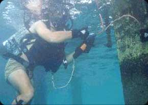 An Army diver sets an underwater demolition charge on the hull of an old ship. Army diving students spend five days learning basic engineering skills such as demolitions, land mine warfare, wire obstacles and booby-traps.
