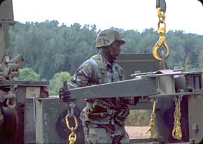 A Bridge Crewmember prepares a PLS (Palettized Loading System) during the construction of a land bridge.